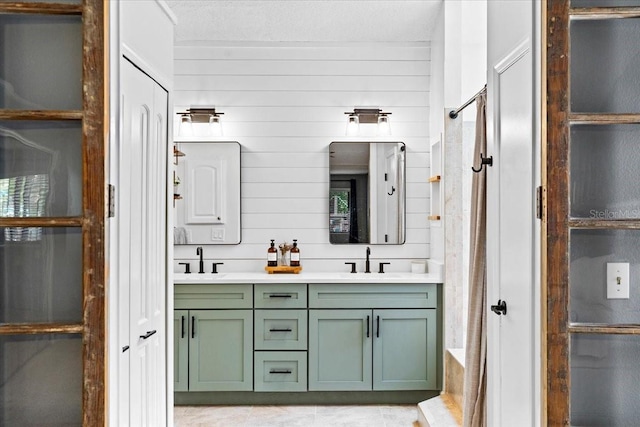 bathroom featuring a sink, a shower, a textured ceiling, and double vanity