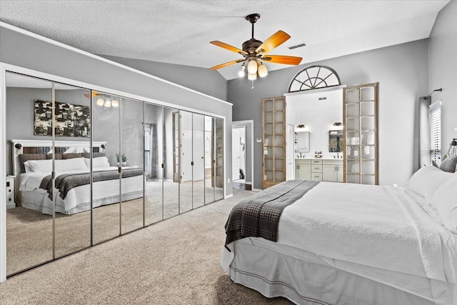 carpeted bedroom featuring visible vents, a ceiling fan, a textured ceiling, ensuite bath, and lofted ceiling