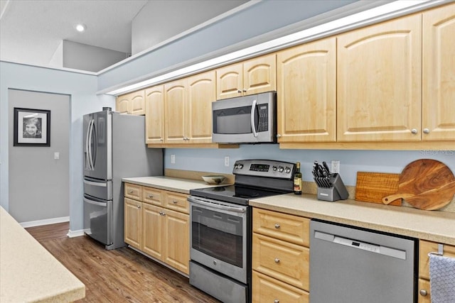 kitchen with dark wood-type flooring, light brown cabinetry, appliances with stainless steel finishes, light countertops, and baseboards