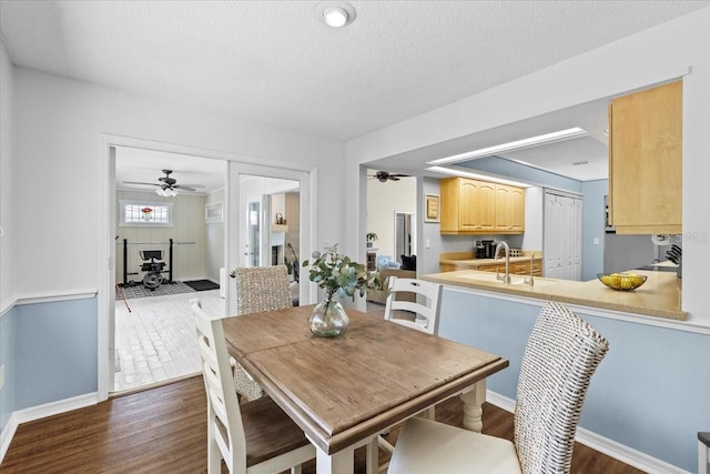 dining area featuring dark wood finished floors, a ceiling fan, baseboards, and a textured ceiling