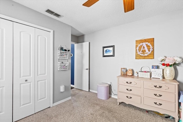 bedroom with visible vents, ceiling fan, a closet, a textured ceiling, and light colored carpet