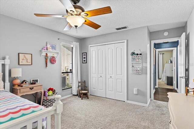 bedroom with visible vents, carpet, a closet, and a textured ceiling