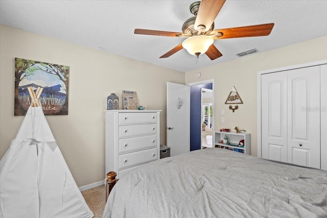 carpeted bedroom with visible vents, a ceiling fan, a textured ceiling, a closet, and baseboards