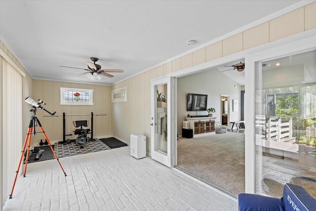 exercise room featuring brick floor, a ceiling fan, and ornamental molding