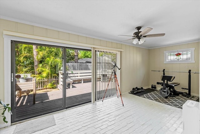 exercise room with a ceiling fan and brick floor