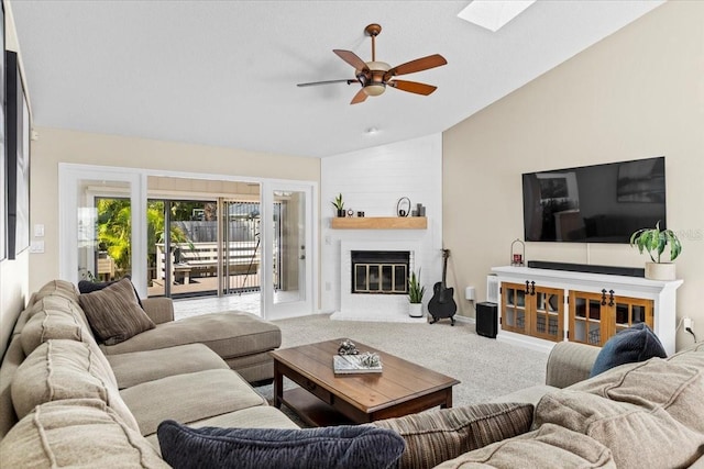 carpeted living room featuring baseboards, a ceiling fan, a fireplace, and vaulted ceiling