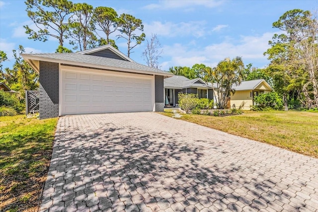 ranch-style house with a front yard, decorative driveway, brick siding, and a garage