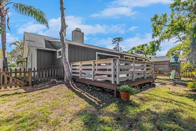 exterior space featuring a lawn, a chimney, a deck, and fence