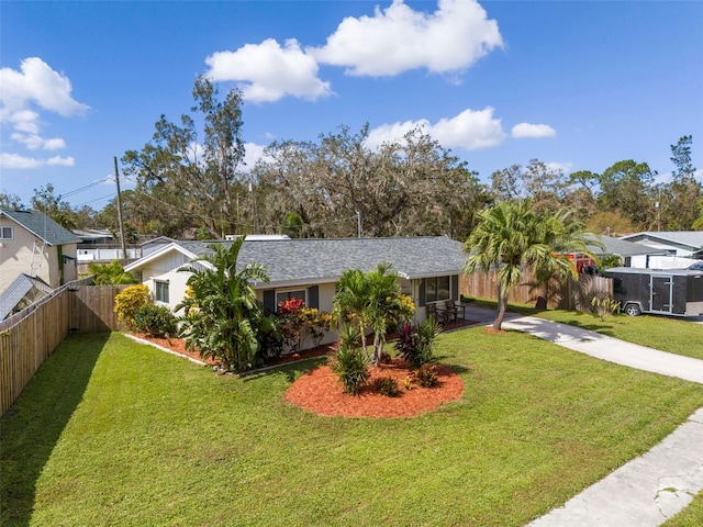 ranch-style house featuring roof with shingles, concrete driveway, a front yard, and fence