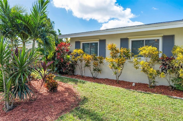 view of side of home with stucco siding and a yard