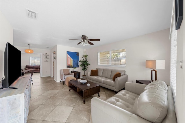 living area featuring light tile patterned floors, visible vents, and ceiling fan