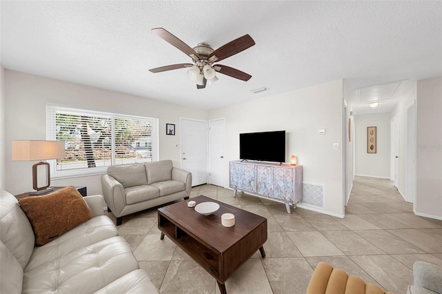 living room featuring visible vents, attic access, a textured ceiling, and ceiling fan