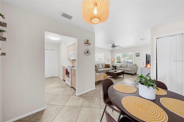 dining area featuring a ceiling fan, light tile patterned flooring, baseboards, and visible vents