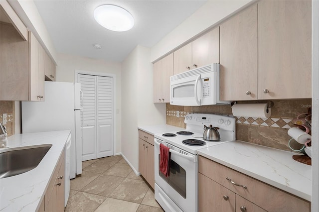 kitchen with decorative backsplash, white appliances, light brown cabinetry, and a sink