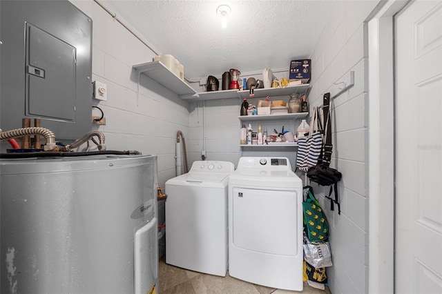 clothes washing area with concrete block wall, laundry area, electric panel, water heater, and washer and dryer