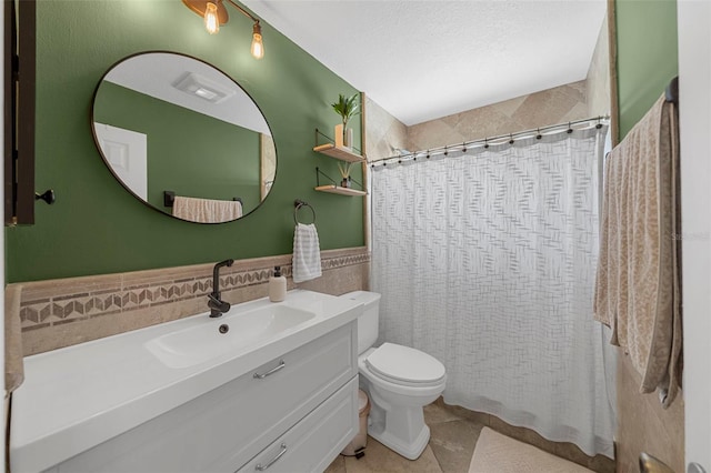 full bath featuring a shower with curtain, toilet, a textured ceiling, tile walls, and vanity