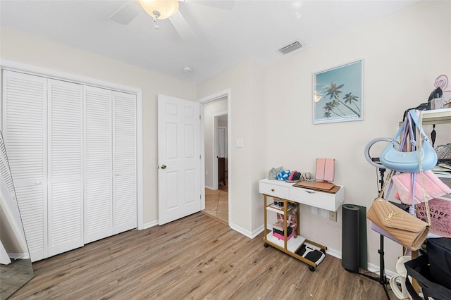 interior space featuring ceiling fan, visible vents, baseboards, and wood finished floors