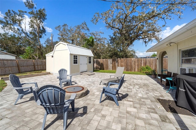 view of patio / terrace featuring a storage unit, an outbuilding, a fire pit, and a fenced backyard