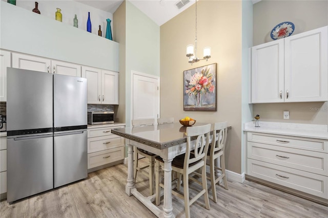 kitchen featuring visible vents, light wood-style flooring, white cabinets, appliances with stainless steel finishes, and a chandelier