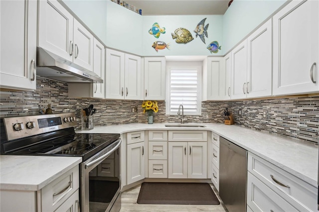 kitchen featuring under cabinet range hood, a sink, appliances with stainless steel finishes, white cabinets, and decorative backsplash