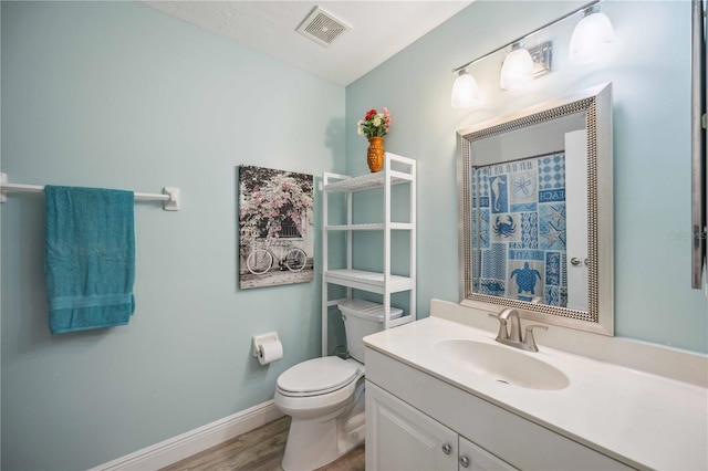 full bath with vanity, wood finished floors, visible vents, baseboards, and toilet