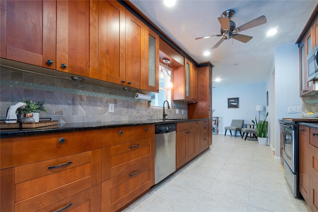 kitchen featuring tasteful backsplash, brown cabinets, stainless steel appliances, a ceiling fan, and a sink