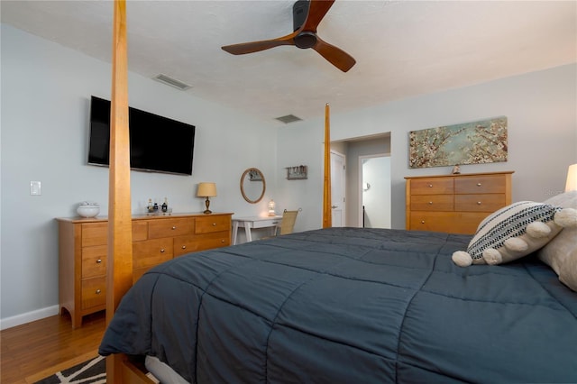 bedroom featuring a ceiling fan, wood finished floors, visible vents, and baseboards