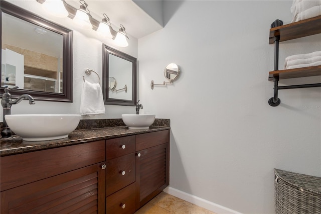 bathroom with double vanity, baseboards, tile patterned floors, and a sink