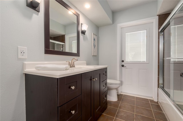 bathroom featuring vanity, tile patterned floors, toilet, and bath / shower combo with glass door