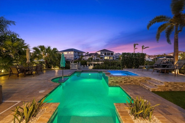 view of pool featuring a patio, fence, outdoor dining space, and a pool with connected hot tub