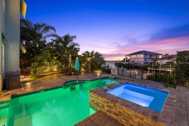 view of pool featuring a patio area, fence, and a pool with connected hot tub