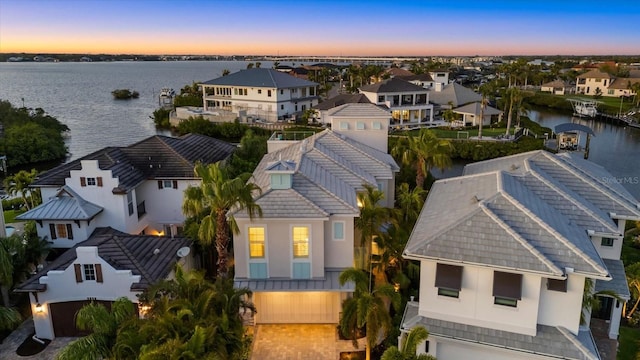 aerial view at dusk with a residential view and a water view