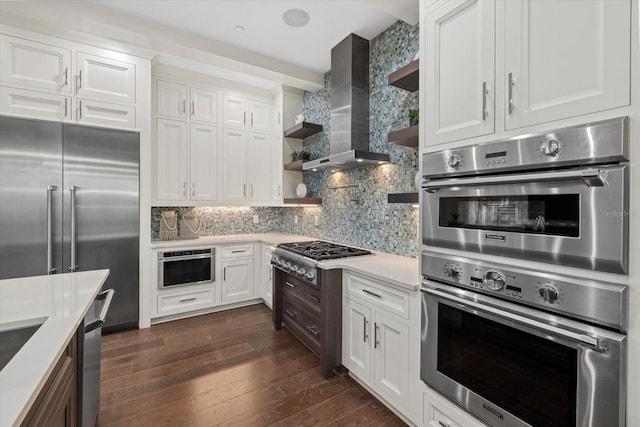 kitchen featuring open shelves, wall chimney range hood, dark wood-style floors, stainless steel appliances, and light countertops