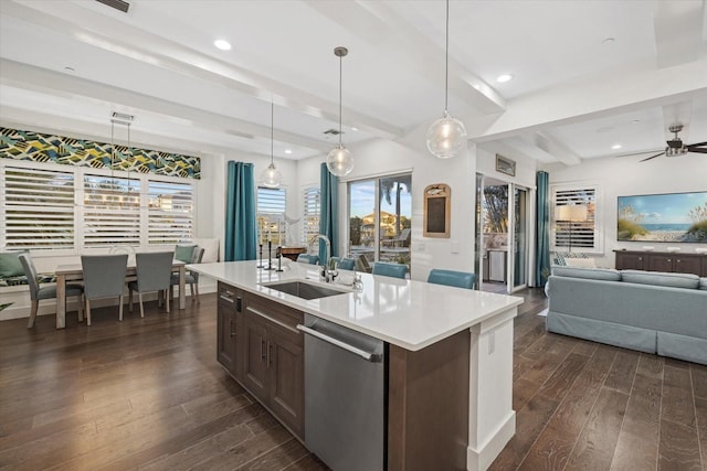 kitchen with a sink, light countertops, dark wood-type flooring, and stainless steel dishwasher