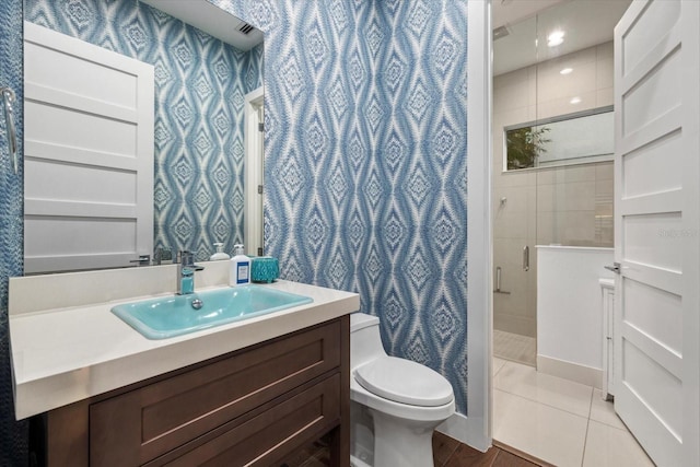 bathroom featuring tile patterned flooring, a shower stall, wallpapered walls, toilet, and vanity