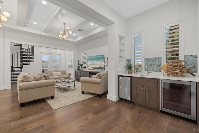 living room featuring dark wood-style floors, wine cooler, an inviting chandelier, indoor wet bar, and stairs