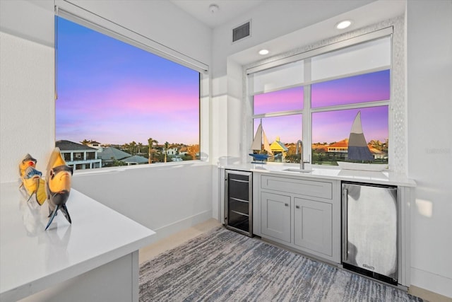 bar featuring beverage cooler, visible vents, recessed lighting, a sink, and stainless steel refrigerator