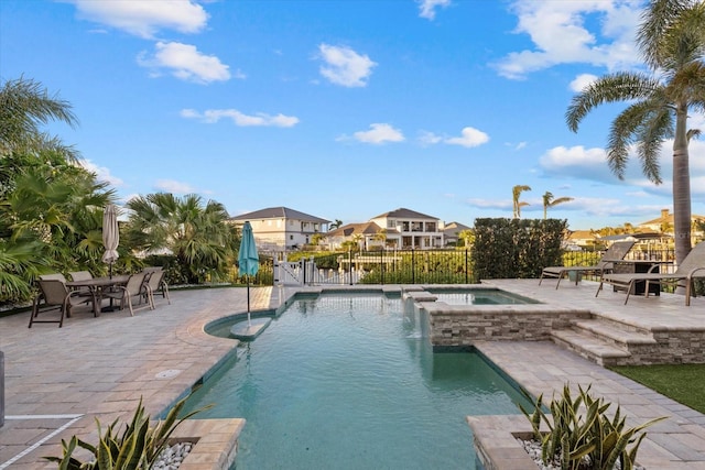 view of pool with a pool with connected hot tub, a patio, and fence