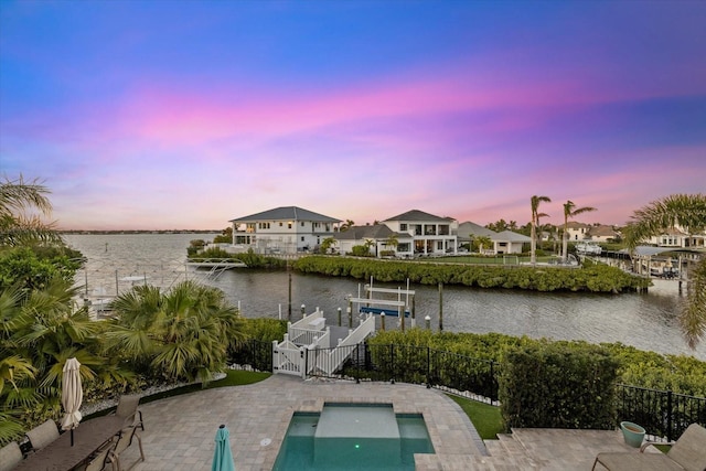 exterior space featuring a water view, a patio, a dock, fence, and boat lift