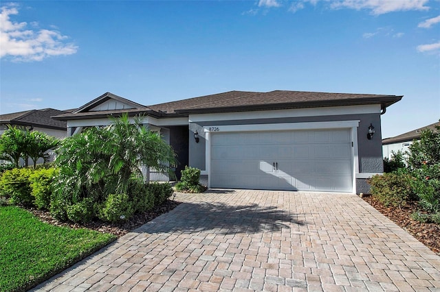 ranch-style house featuring decorative driveway, a garage, and stucco siding