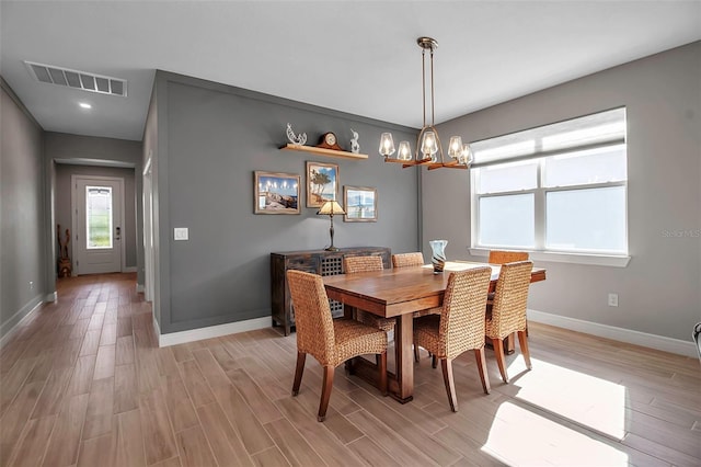 dining area with visible vents, baseboards, an inviting chandelier, and light wood-style flooring