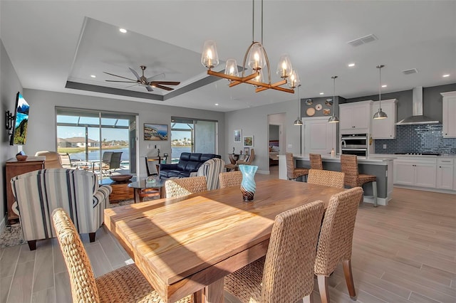 dining area with recessed lighting, visible vents, ceiling fan with notable chandelier, and a tray ceiling