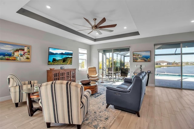 living area featuring a tray ceiling, a ceiling fan, a sunroom, and wood finish floors