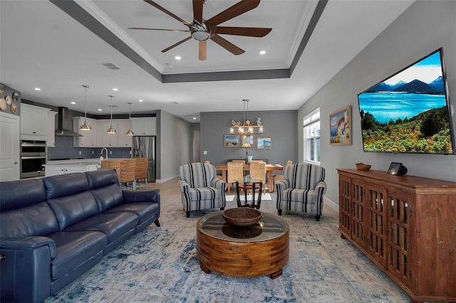 living room with baseboards, visible vents, a tray ceiling, recessed lighting, and ornamental molding