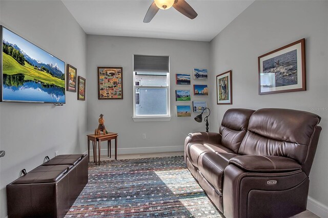 living area with baseboards and ceiling fan