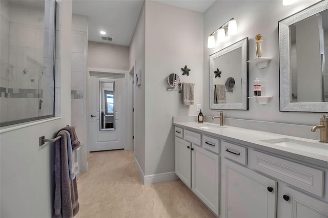 bathroom with double vanity, tiled shower, visible vents, and a sink