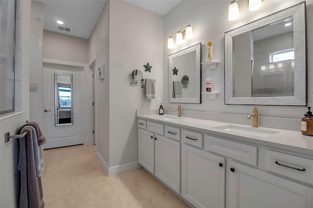 full bath featuring baseboards, tiled shower, visible vents, and a sink