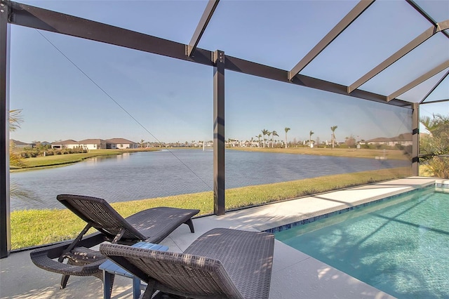 outdoor pool featuring glass enclosure, a water view, and a patio