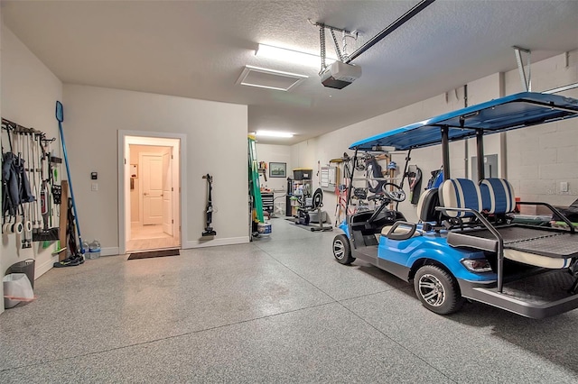 garage with concrete block wall, a garage door opener, and baseboards