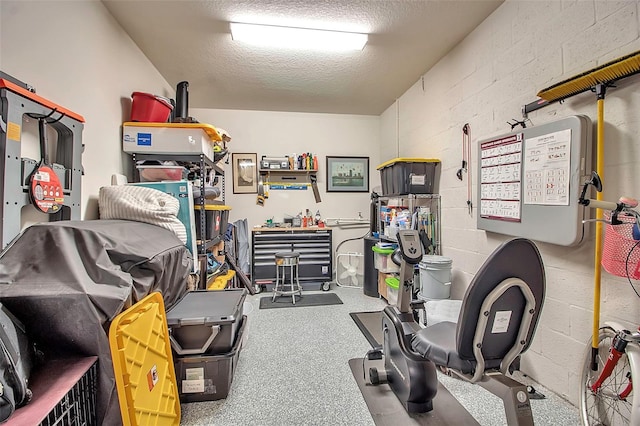 exercise room featuring a textured ceiling and concrete block wall